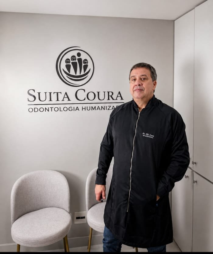 Dr. Élio Coura em frente à logo da Suíta Coura Odontologia